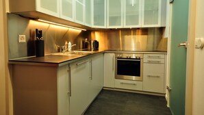 Una cocina moderna con armarios blancos, electrodomésticos de acero inoxidable y un horno empotrado.