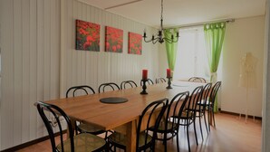 Comedor con una mesa de madera, sillas negras y velas rojas.