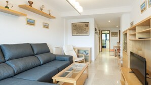 A modern living room with a grey sofa, wooden coffee table, and a flat-screen TV. - ALEJANDRITA - Apartment with shared pool in Playa De Gandia and Free Wifi (Gandia)