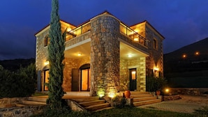 A stone house with a balcony, a staircase leading to the entrance, and a well-lit front porch. - Villa Erato / Private Paradise with heatable Pool &   Sea View. (Koutouloufari)