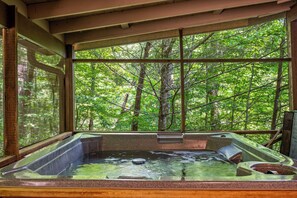 A hot tub with a view of a dense forest through large windows. - Perfect mountain cottage ☎ Fire pit ☎ Gas Fireplace ☎ Screened Porch ☎ Secluded (Townsend)