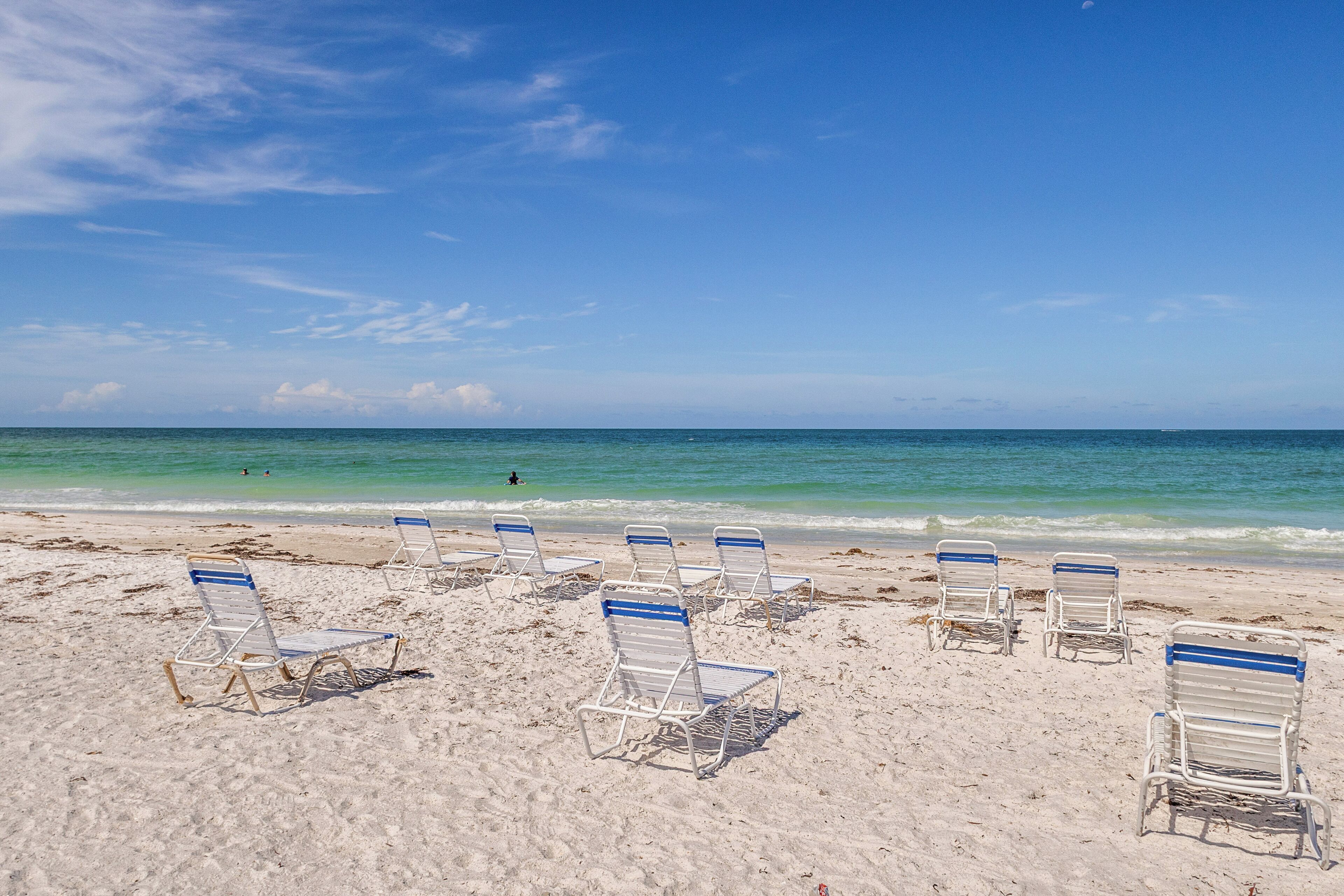 Ein Strand mit mehreren Reihen leerer Liegen und freiem Blick auf das Meer.