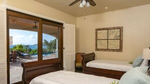 A bedroom with two wooden beds, a ceiling fan, and a large window overlooking a pool and mountains. - Francis Bay Estate: Luxury Villa! Pool! Walk To The Beach! (Mary Point)