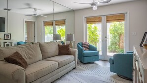 Un soggiorno con un divano beige, una poltrona blu e una ventola a soffitto.