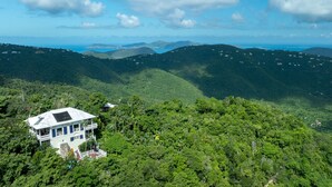 Ein Haus mit einem gro ßen Balkon, umgeben von dichtem Wald und Hügeln.