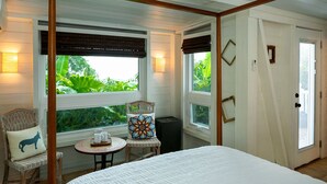 Ein Schlafzimmer mit einem großen Bett, einem kleinen Tisch mit zwei Tassen, einem Sessel und einem Fenster mit Jalousien.