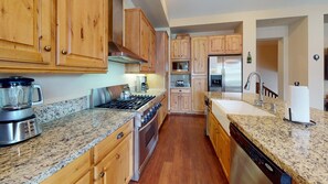 A kitchen with wooden cabinets, granite countertops, stainless steel appliances, and a dishwasher.