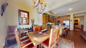 A dining area with a wooden table and chairs, a chandelier, and a mirror on the wall. - Snowcreek Resort Vacation Rental 1152 (Mammoth Lakes)