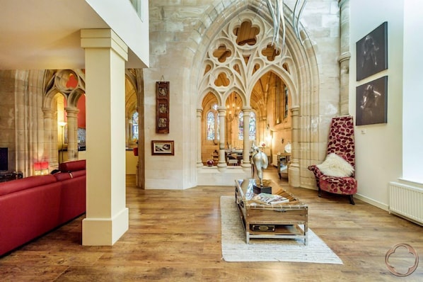 Un intérieur spacieux avec un canapé rouge, une table basse en bois et un fauteuil à motifs.
