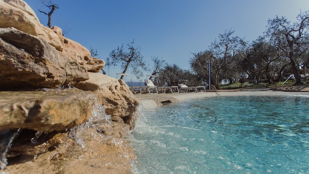 Une piscine aux eaux cristallines, agrémentée de rochers et d’un espace de détente avec des fauteuils.