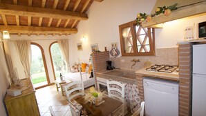 Une cuisine équipée d’une cuisinière à gaz, d’un lave-vaisselle et d’un réfrigérateur. On y trouve une table à manger avec des chaises, ainsi qu’une fenêtre avec des rideaux.