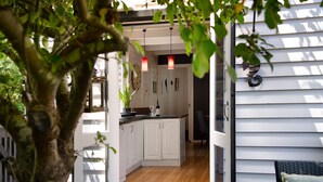 Een moderne keuken met witte kastjes, een houten aanrechtblad, hanglampen en een potplant.
