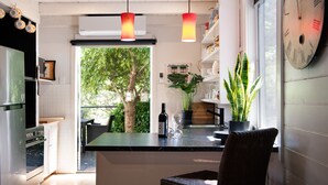 Een moderne keuken met een marmeren aanrecht, hanglampen, een koelkast en een potplant.