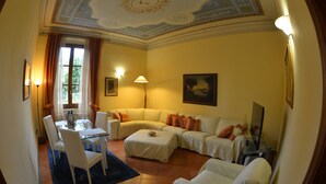 Una sala de estar con sofá, reposapiés y una mesa de comedor con sillas.