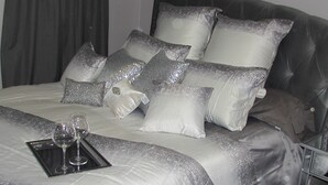 A neatly made bed with a silver and white bedding set, a tray with wine glasses, and a dark-colored headboard. - !!NEW!! Luxurious remodeled home !! No cleaning fee! (Idaho Falls)