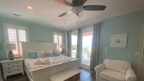 A bedroom with a bed, a bench, a nightstand, a chair, and a ceiling fan. - BEST DEAL IN KURE BEACH!!! FULLY RENOVATED LUXURY HOME STEPS TO THE OCEAN & PIER (Kure Beach)