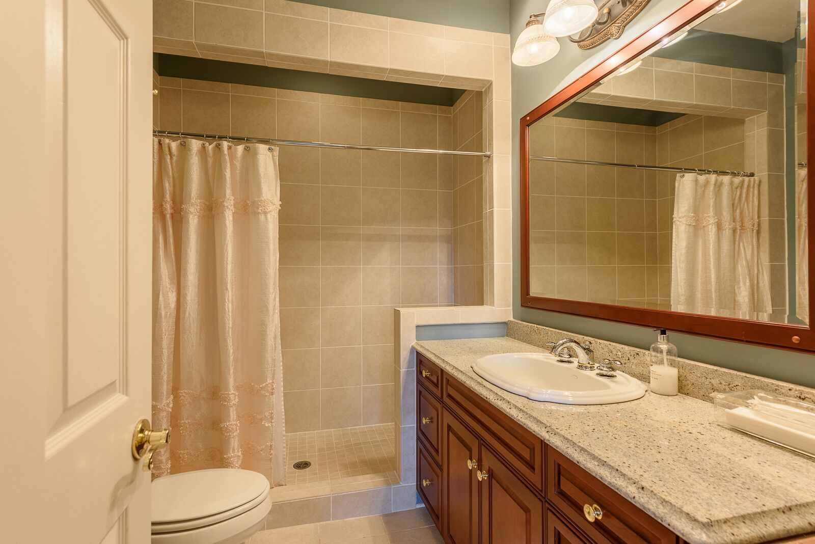 Un baño con ducha, inodoro, lavamanos y tocador.