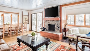 Un salon chaleureux avec une cheminée, des meubles en bois et une grande fenêtre.