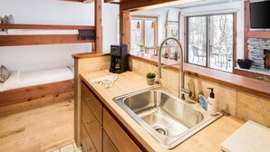 Une cuisine moderne dotée d’un plan de travail en bois, d’un évier en acier inoxydable et d’armoires en bois.