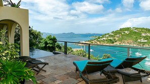 An outdoor seating area with wicker chairs and a view of the sea.