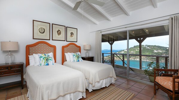 A hotel room with two beds, a balcony with a view, and artwork on the wall.