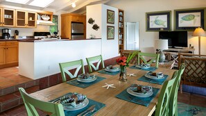 A dining area with a wooden table set for a meal, surrounded by green chairs.