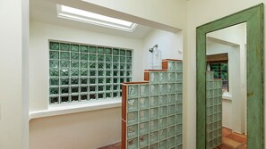 A hallway with a window, a mirror, and a tiled wall.