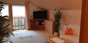 A living room with a television, speakers, a sofa, a coffee table, and a potted plant. - Top 6 - House Annette (Schröcken)