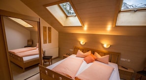 Um quarto com um claraboia, uma cama com almofadas, uma cadeira e uma mesa de cabeceira.