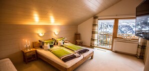 A bedroom with a wooden ceiling, a bed with green bedding, a nightstand with candles, and a view of snowy mountains through a balcony. - Top 6 - House Annette (Schröcken)