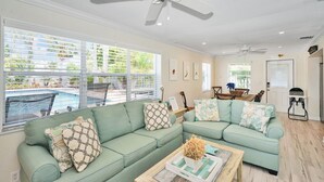 A living room with two light green sofas, a coffee table, and a ceiling fan. - Blue Pearl for 10-Heated Pool-Beach-Pier 5 minutes (Pompano Beach)