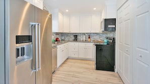 A modern kitchen with white cabinets, stainless steel appliances, and a tiled backsplash. - Blue Pearl for 10-Heated Pool-Beach-Pier 5 minutes (Pompano Beach)