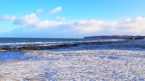 Eine Küstenlandschaft mit blauem Himmel, einem Sandstrand und einer fernen Küste.