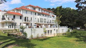 Ein mehrstöckiges Gebäude mit Balkonen, einer Stein-Fassade und einem gepflegten Rasen.