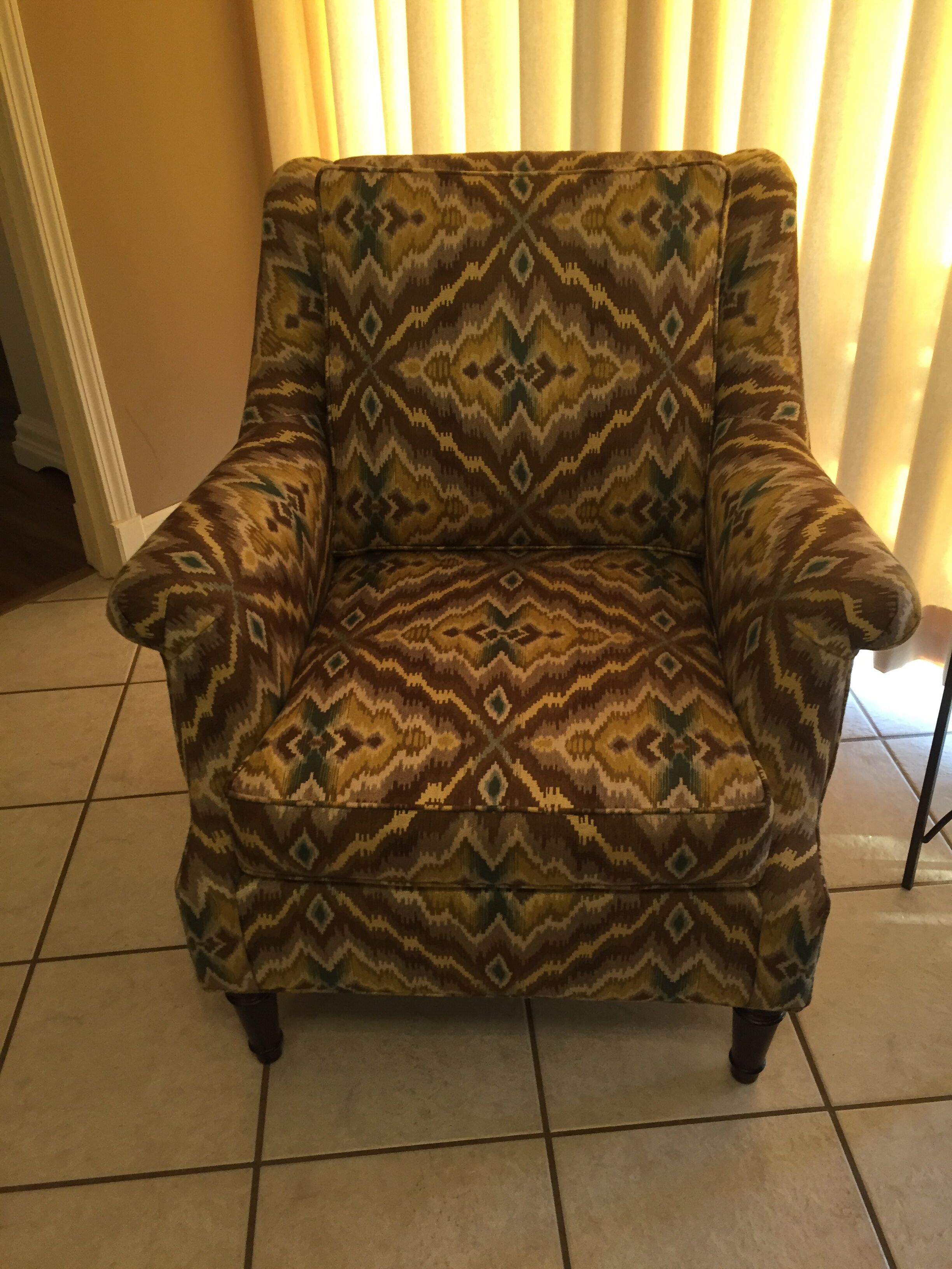 Un sillón con estampado y diseño geométrico, sobre un piso de baldosas.