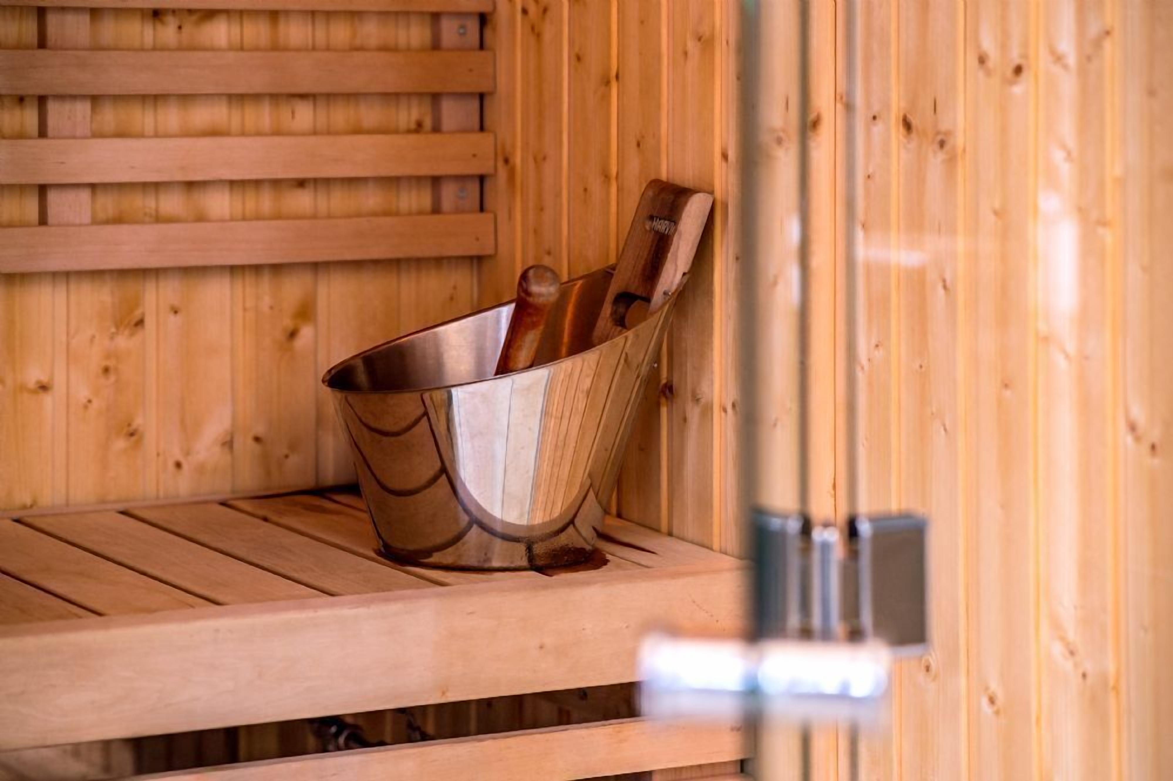 Un sauna en bois avec un seau en métal contenant des bâtons de bois.