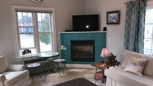 Ein Wohnzimmer mit Kamin, Fernseher, Sofa, Tisch und Stuhl.