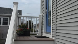 Ein Wohnhaus mit Veranda, einer blauen Tür und einem weißen Geländer.