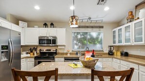 A modern kitchen with white cabinets, stainless steel appliances, and a granite countertop.