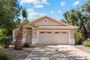 A single-story house with a beige facade, a tiled roof, and a garage.