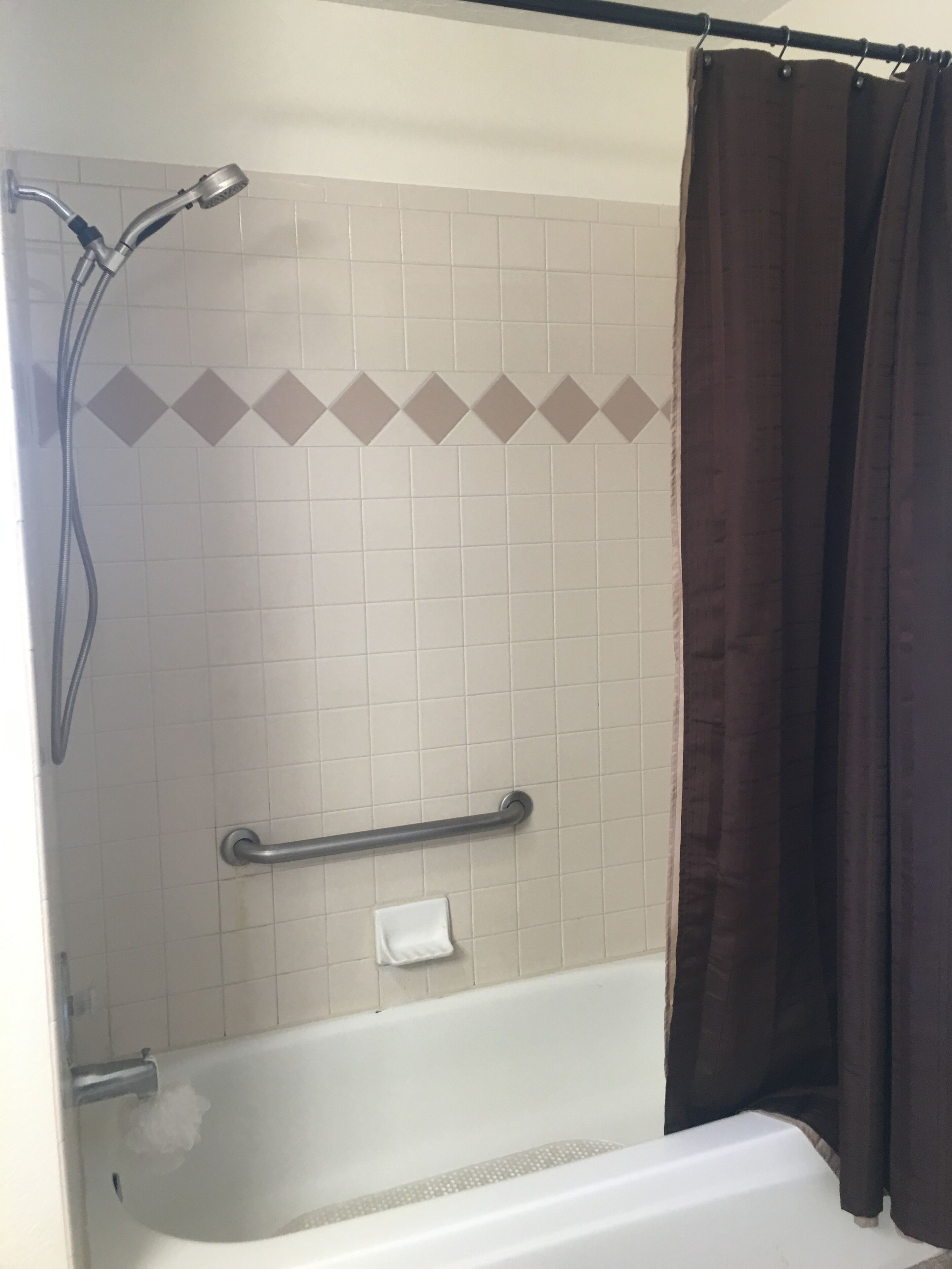A bathroom with a shower, a bathtub, a grab bar, and a towel rack.