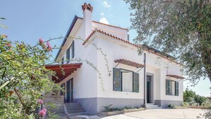 A two-story house with a white facade, green shutters, and a tiled roof.