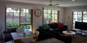 Ein Wohnzimmer mit einer Couch, einem Couchtisch, einem Fernseher und einem Essbereich mit Tisch und Stühlen.