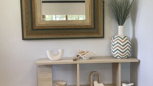 A wooden console table with decorative items, a mirror, and a vase with greenery. - Cowes Chapel Beach House (Cowes)