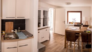 Moderni keittiö, jossa on valkoiset kaapit, puinen työtaso sekä ruokailutila, jossa on puinen pöytä ja tuolit.