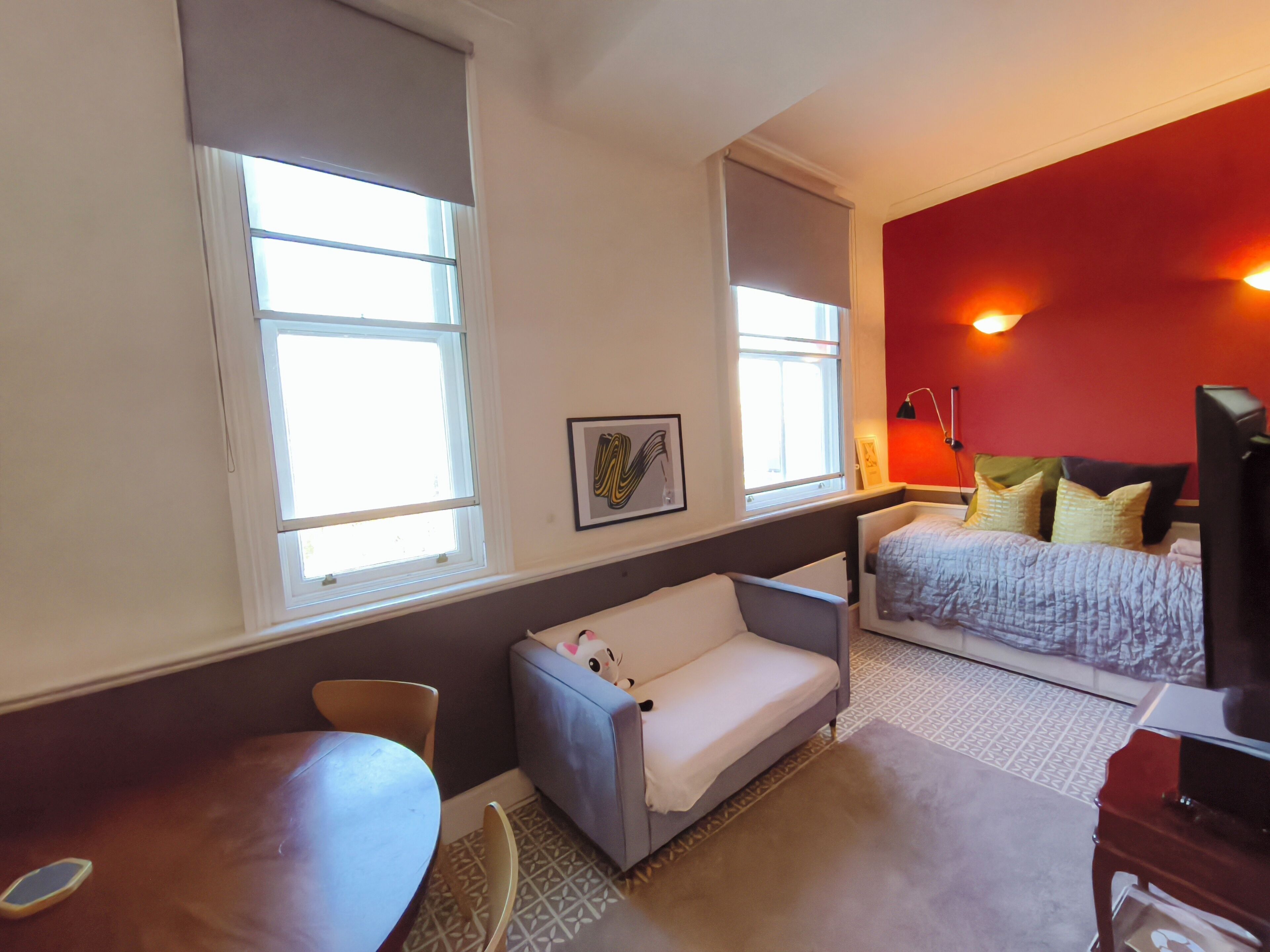 A compact room with a bed, a sofa, a desk, and a chair.