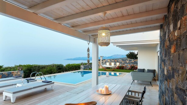 A poolside area with lounge chairs, a table with candles, and a view of the sea. - Villa Greece Privat Seaview Villa with private heatable Pool  (Hersonissos)