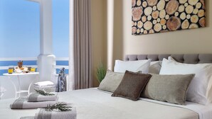 A hotel room with a bed, pillows, a view of the sea, a table with a drink, and a painting on the wall. - Villa Greece Privat Seaview Villa with private heatable Pool  (Hersonissos)