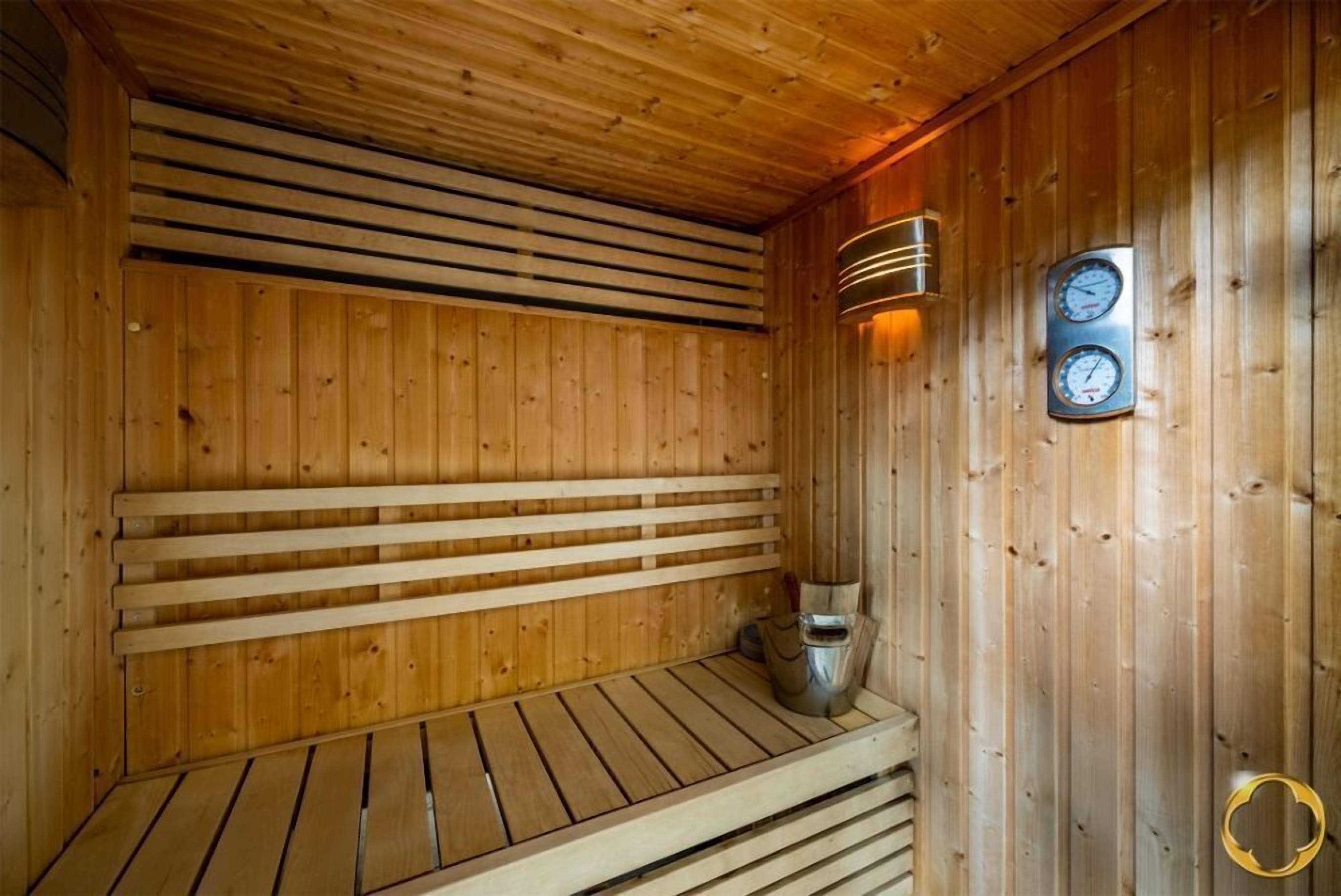 Eine Holzsauna mit Bänken und einem an der Wand montierten Ofen.