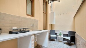 Una cucina compatta con lavello, fornelli e un piccolo angolo ristoro con due sedie e un tavolo.